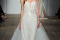 22 white strapless wedding gown with a covered plunging neckline, a flower on the waist and a detachable skirt by Lazaro