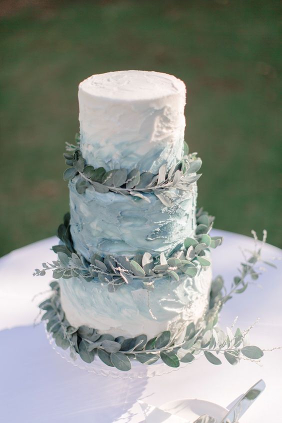 a textural blue watercolor wedding cake decorated with eucalyptus