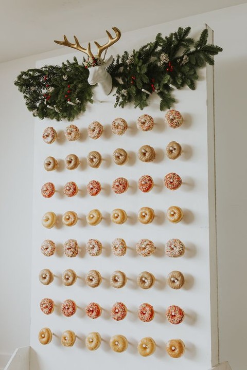 a Christmas donut wall with fir branches and a faux deer head