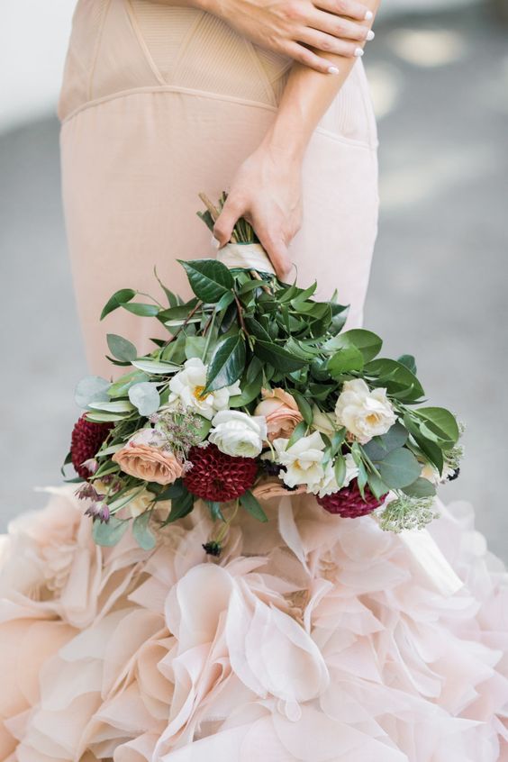 a bride in a blush mermaid wedding dress with a blush, cream and marsala bouquet