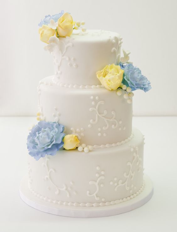 a creamy textural wedding cake with blue and yellow sugar flowers