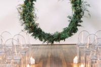 24 a minimalist wedding ceremony space with a suspended circle wedding arch, acrylic chairs and candles