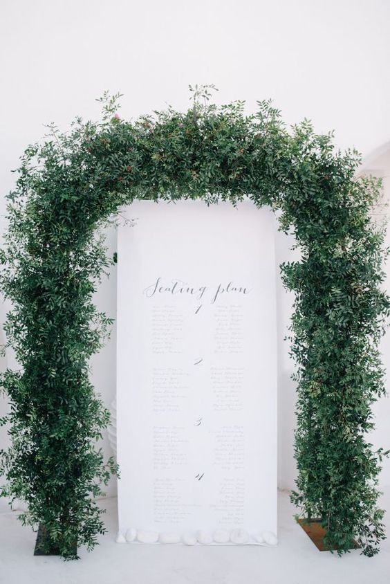 a printed seating plan surrounded with a large lush greenery garland for a fresh feel