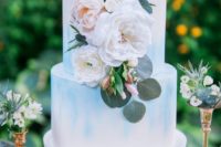 25 a white wedding cake with watercolor blue touches and lush florals