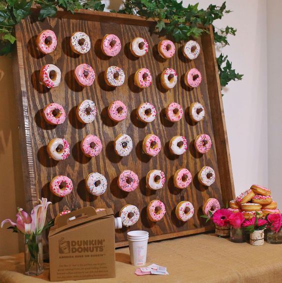 a mini donut wall decorated with fresh greenery and with fresh blooms around