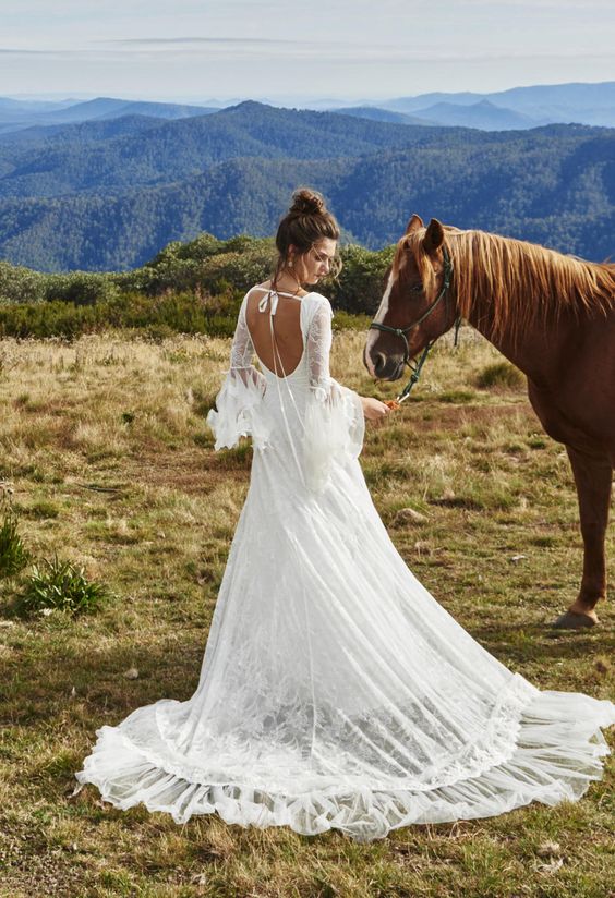 country wedding dress with a cutout back, bell sleeves, a full overskirt and a bow on the back
