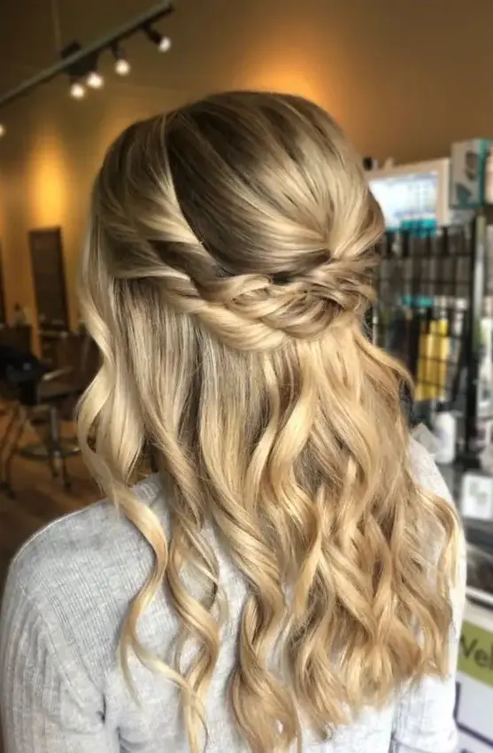 a blonde bridal half updo with a bump on top and a double twisted halo plus some waves down is a cool and lovely idea for a boho or rustic bride