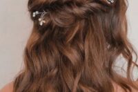 a brunette half updo with a twisted double halo and waves down, with pearl and rhinestone hair pins is chic and cool