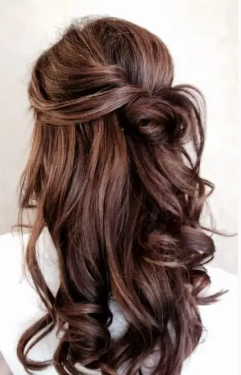 a chic and a bit messy half updo with a volume on top, a messy knot and waves down looks very romantic and lovely