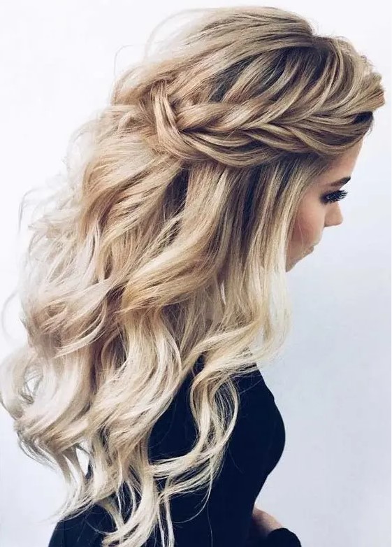 a chic half updo with braids on the front, waves down and a messy volume on top for a romantic bride