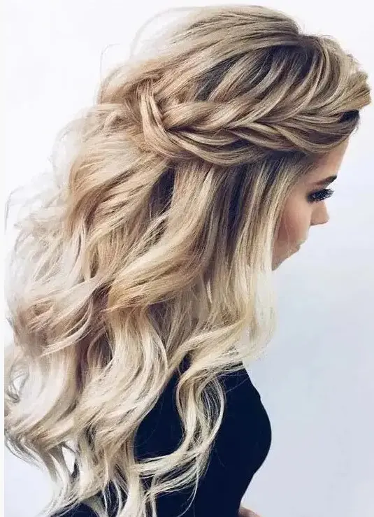 a chic wedding half updo with braids on the front, waves down and a messy volume on top for a romantic person