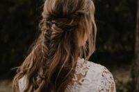 a cool boho half updo with a double braided halo and a fishtail braid and waves down is a cool idea for a boho bride or bridesmaid