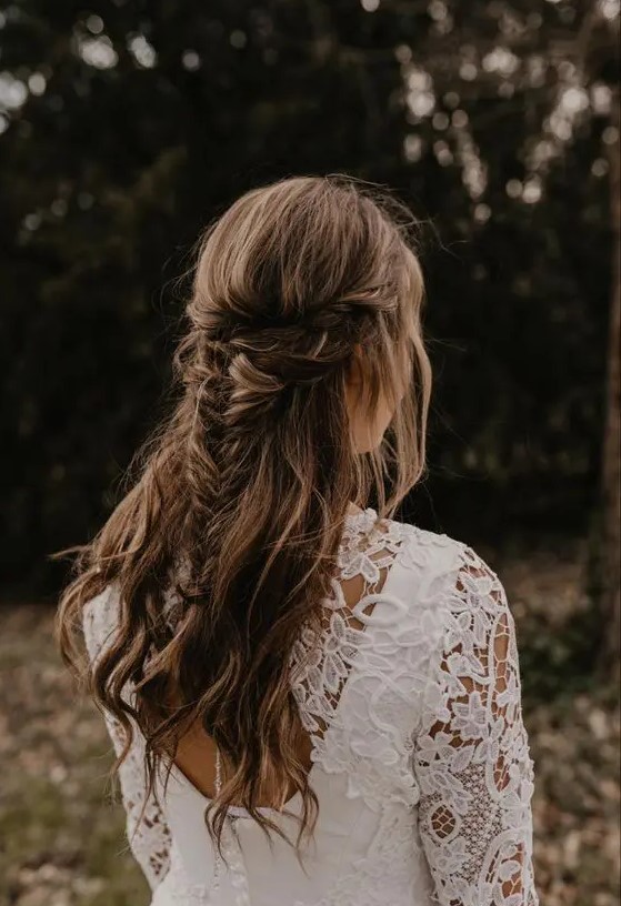 a cool boho half updo with a double braided halo and a fishtail braid and waves down is a cool idea for a boho bride or bridesmaid