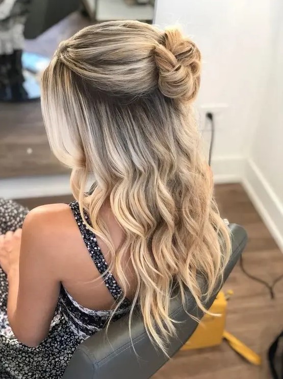 a cute half updo with a volume on top, a top bun and waves down including those framing the face