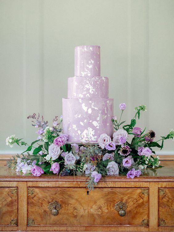 a lilac wedding cake with silver foil and purple and lilac blooms around is a refined idea