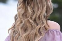 a lovely boho hairstyle with a fishtail braid halo, a large knot and waves down is amazing