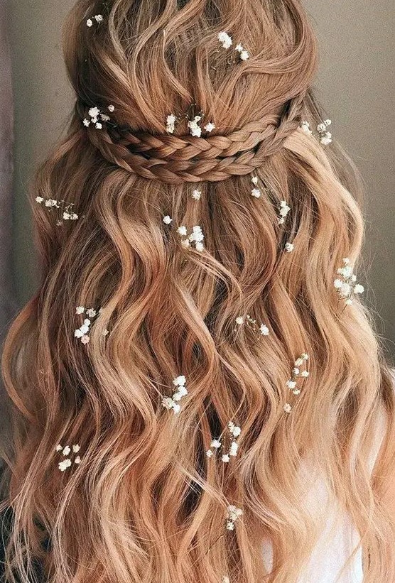 a lovely half updo with a braided halo, waves down and some baby's breath tucked into the hair is idea for summer
