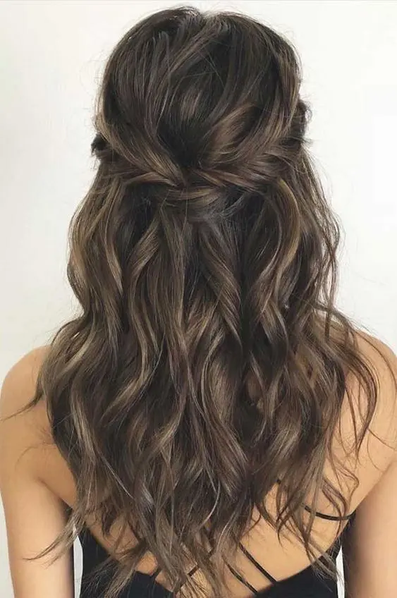 a messy and textured half updo with a fishtail braided halo, a bump on top and waves down is wow