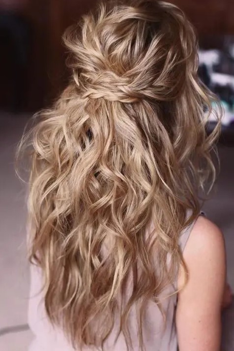 a messy and wavy half updo with two braids as a halo and waves down is a beautiful idea for a boho bride or bridesmaid