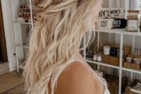 a messy boho half updo with a wavy tpo, a braided and twisted halo and waves down is a cool idea for a boho look