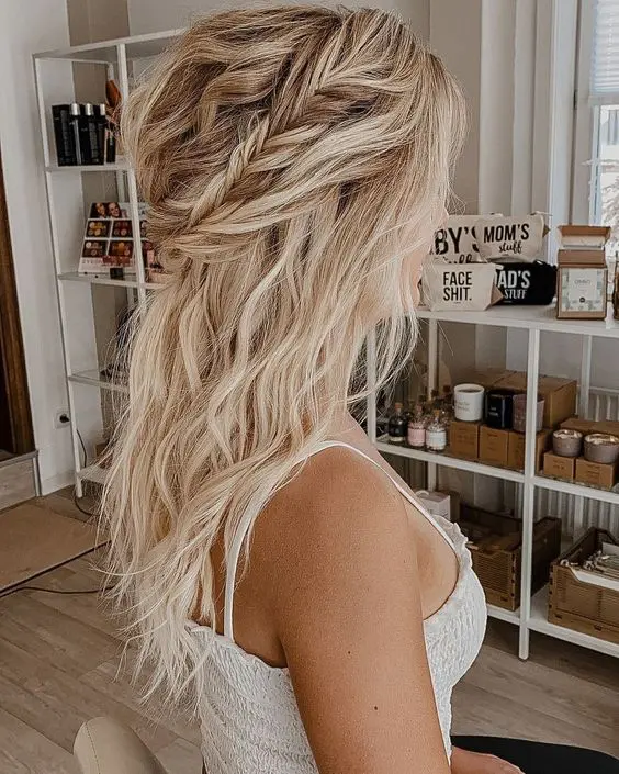 a messy boho half updo with a wavy tpo, a braided and twisted halo and waves down is a cool idea for a boho look