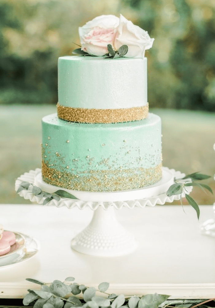 a mint-colored wedding cake with gold glitter, blush and white roses is very glam and elegant