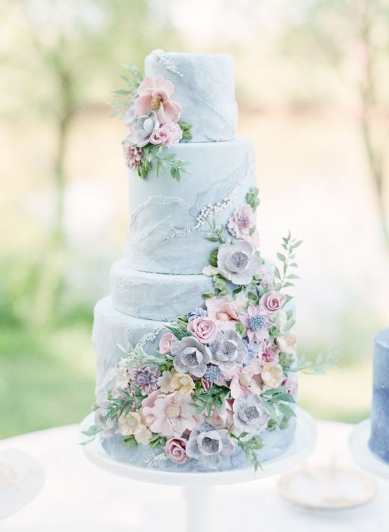 a pastel blue wedding cake decorated with a lot of pastel sugar blooms and greenery is a lovely idea for spring