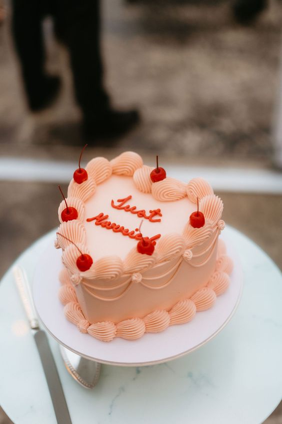 a peachy pink lambeth wedding cake with a calligraphy inscription and cherries