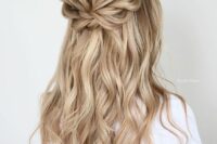 a pretty boho half updo with a dimensional bump, a loose braided halo and waves down is a cool idea for a bride or bridesmaid