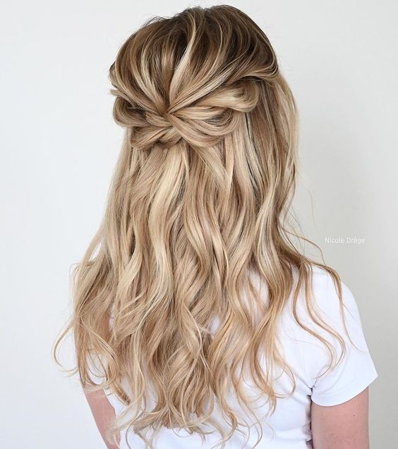 a pretty boho half updo with a dimensional bump, a loose braided halo and waves down is a cool idea for a bride or bridesmaid