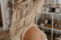 a romantic and relaxed wedding half updo with a twisted and braided halo, with waves down and a messy and wavy bump on top