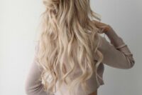 a romantic half updo with a messy and dimensional top, a large wrapped knot, waves down is a beautiful idea