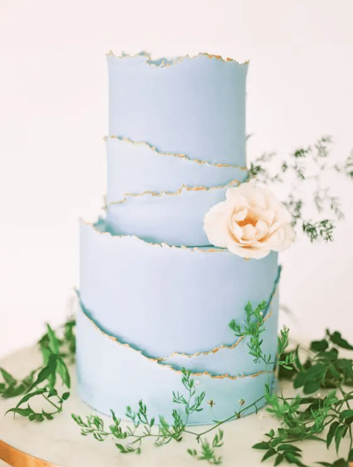 a serenity blue wedding cake with rough gold edges and a peachy bloom is a lovely idea for a spring or summer wedding