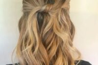 a simple and casual wavy half updo with a bump on top and a knot plus waves down is a stylish idea to rock