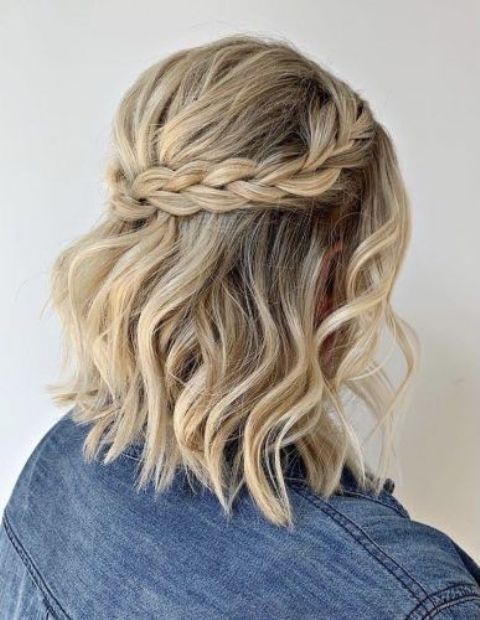 a simple and stylish half updo with waves down, a bump and a braided halo is a cool idea for a bride or bridesmaid
