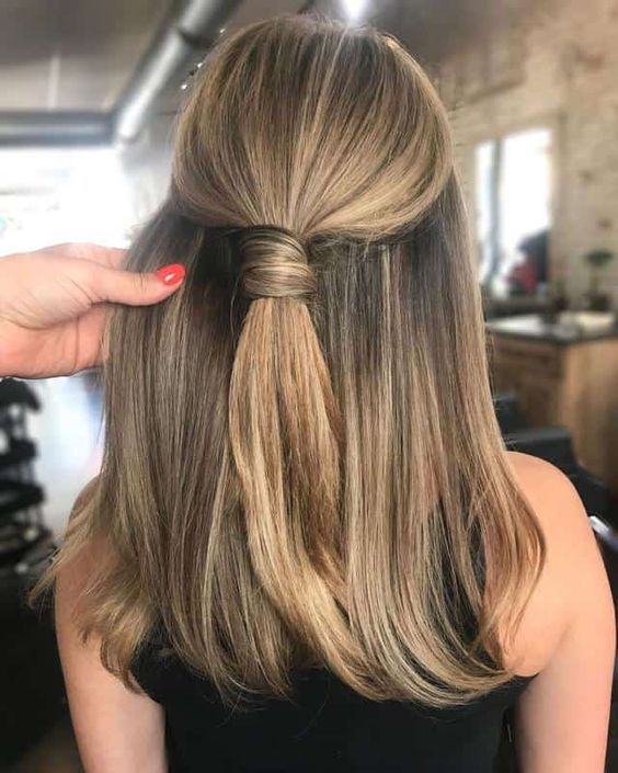 A stylish and cool half updo with a wrapped ponytail on top and straight hair down is a non typical and very modern solution