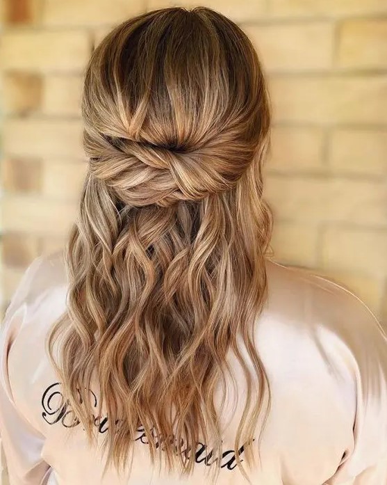a twisted half updo with a bump on top and waves down is a cool idea for both a bride or a bridesmaid