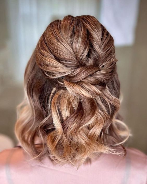 an amazing half updo with a twisted top, a twisted knot and waves down is a cool idea for a boho look