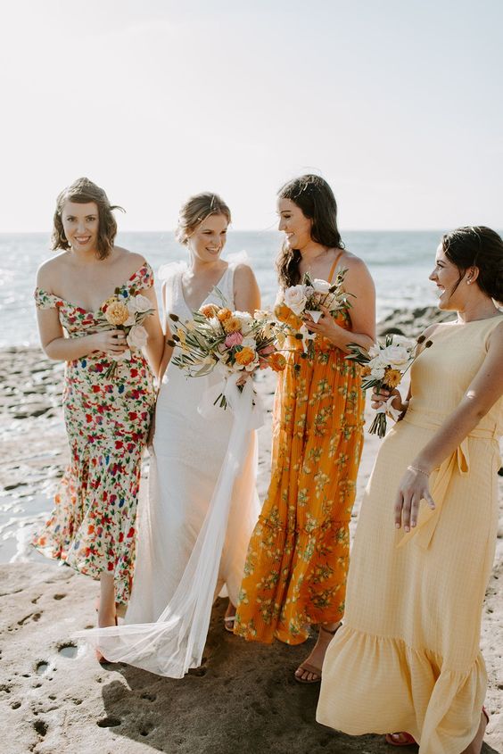 mismatching yellow and orange floral and plain maxi bridesmaid dresses are amazing for a beach wedding