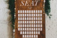 02 a wooden board with a geometric seating chart, a geo banner and a lush greenery garland on top