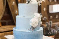 04 a blue watercolor ombre wedding cake topped with white blooms and thistles on top