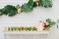04 a tropical wedding bar with colored glasses and a garland of tropical leaves over it