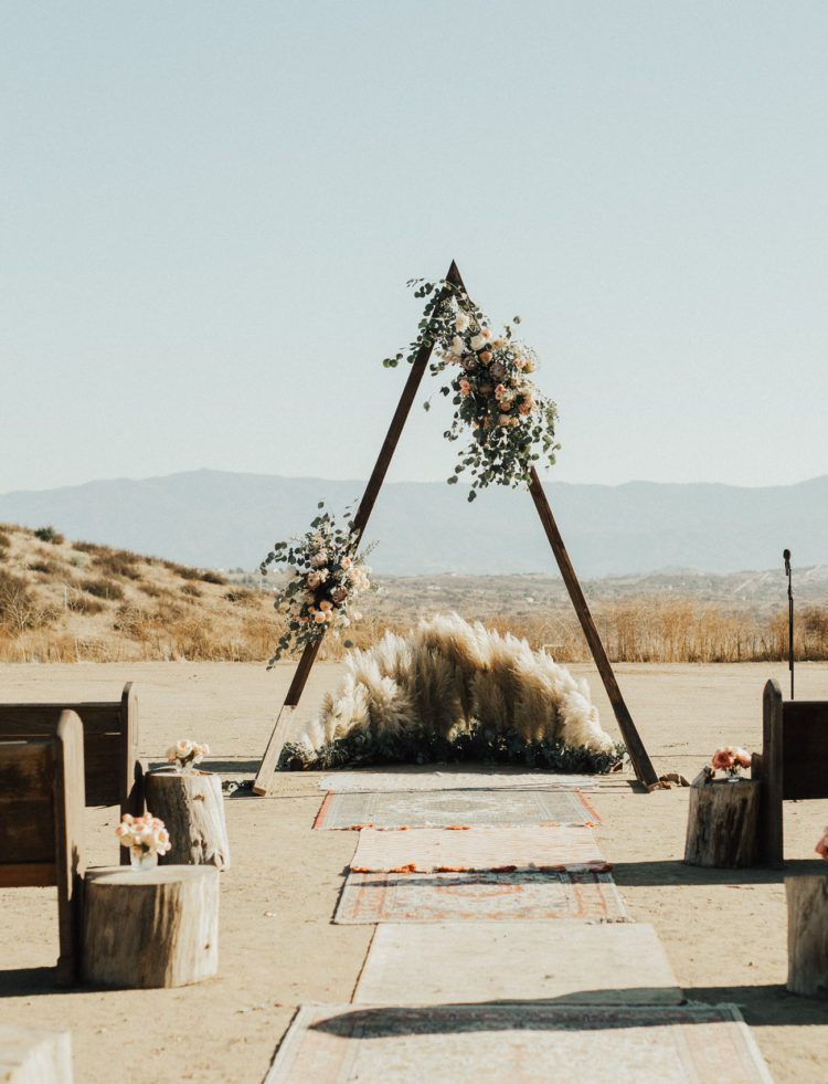 The wedding arch was a triangle one, with greenery and blush roses, pampas grass and rugs