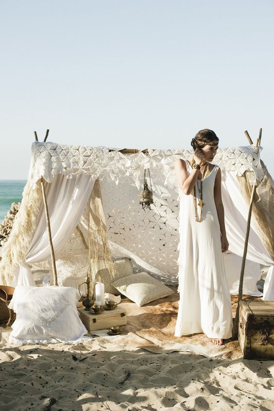 a gorgeous boho wedding teepee with lots of pillows and lanterns for a boho beach wedding