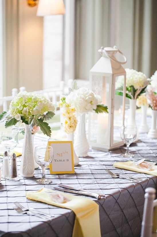 grey and yellow table decor with some floral centerpieces. a white lantern and colored napkins
