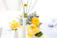 06 a wedding centerpiece with a printed napkin, yellow blooms and pale miller in white vases