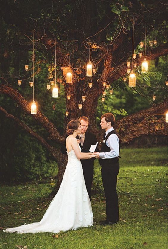 lanterns and candle holders on a tree create a cozy and intimate space ideal for a wedding ceremony