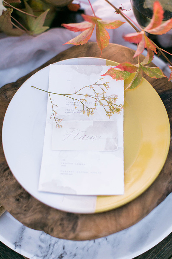 Slight watercolor wedding seating cards and a fall branch decorated the place setting