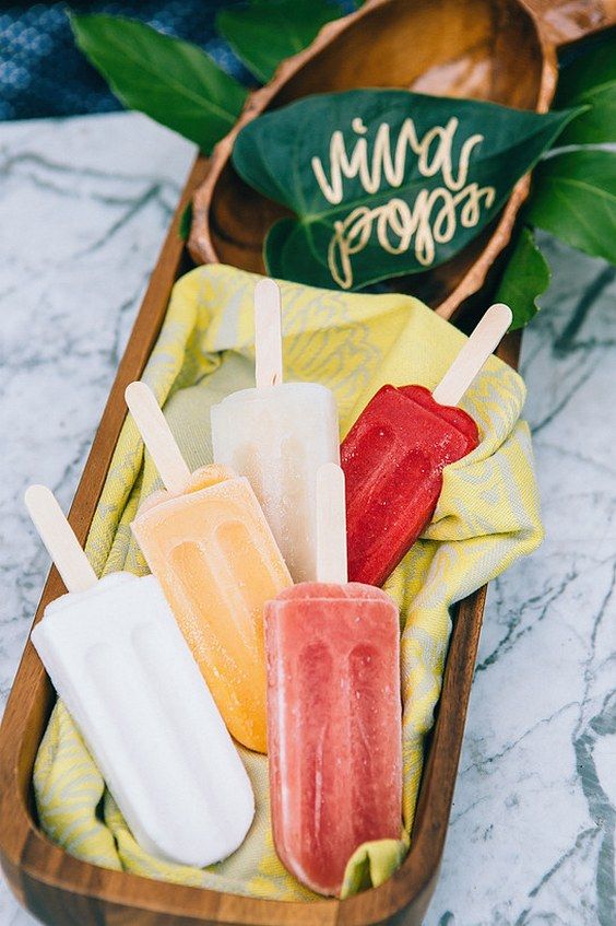 serve fun colorful popsicles with tropical leaves and in a wooden bowl