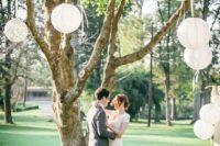 09 paper and macrame lanterns hanging on the tree create a backdrop for a wedding ceremony